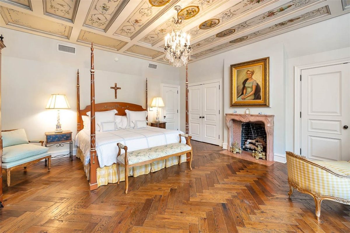 Master bedroom with a chandelier, wood flooring and a fireplace.