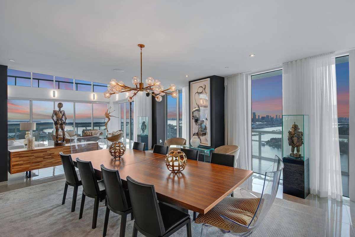 A dining room with a wooden table, surrounded by carefully curated artworks