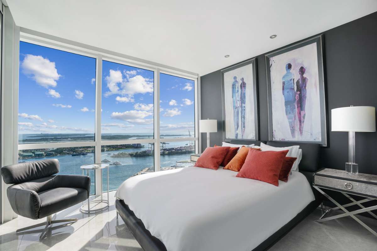 A bedroom with a large window overlooking the ocean