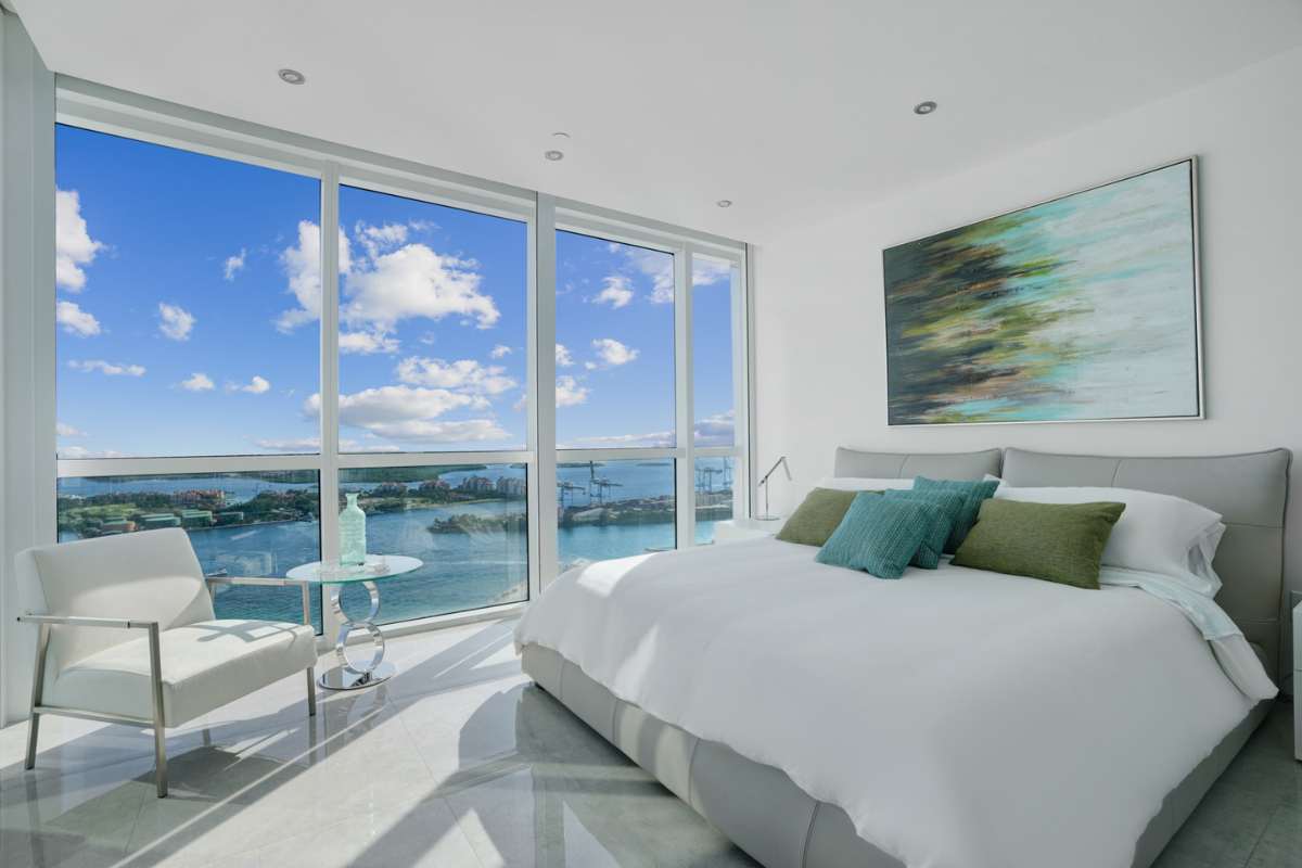 A bedroom with chair, paintings and glass windows