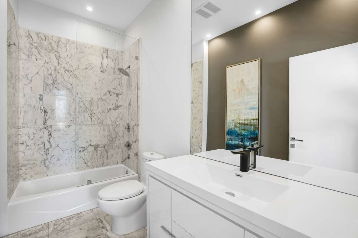 a white bathroom with toilet and bathtub