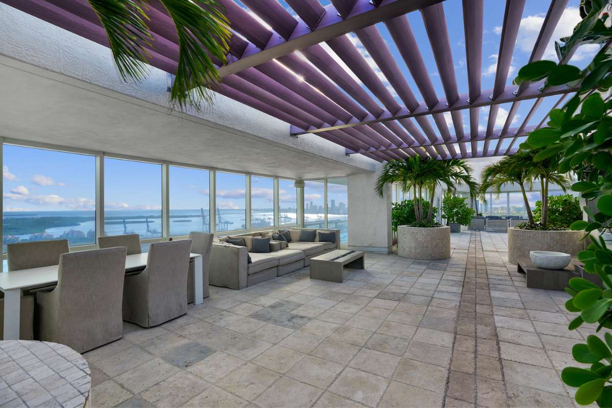 A rooftop terrace with sofa, dining area and plants