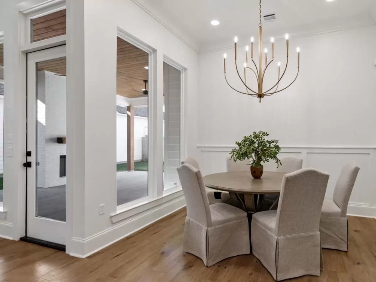 Dining room with a round dining table surrounded by skirted chairs.