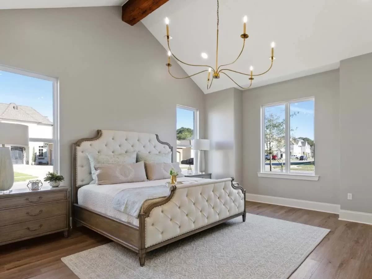 Primary bedroom with a tufted bed and a cathedral ceiling lined with an exposed beam.