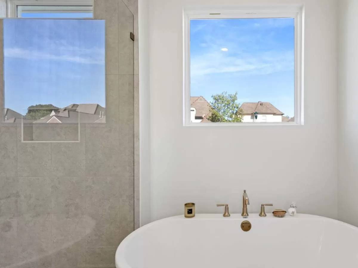 Primary bathroom with a soaking tub and a walk-in shower illuminated by picture windows.