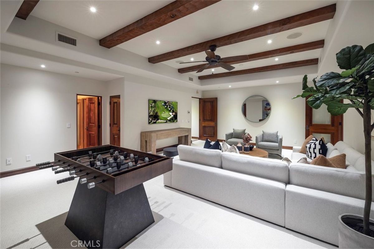 An entertainment room with a TV, couches, a mirror, and white walls and ceiling.