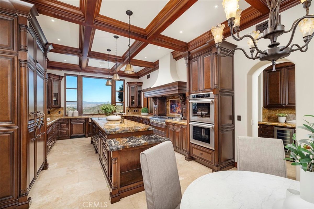 A kitchen with a center island, wooden cabinets, and a wooden beam ceiling.