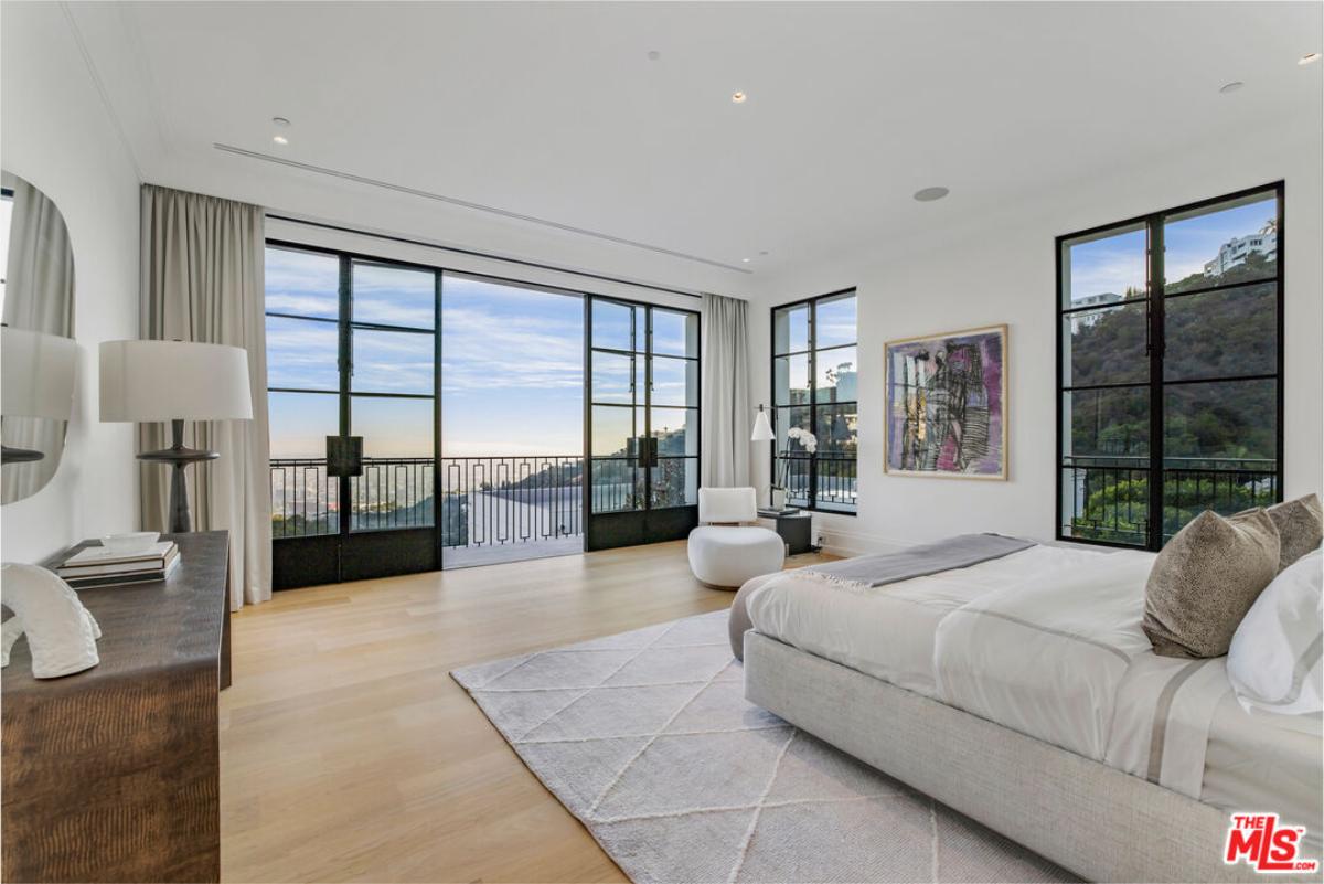 Bedroom with a large bed, sliding glass doors and a balcony.