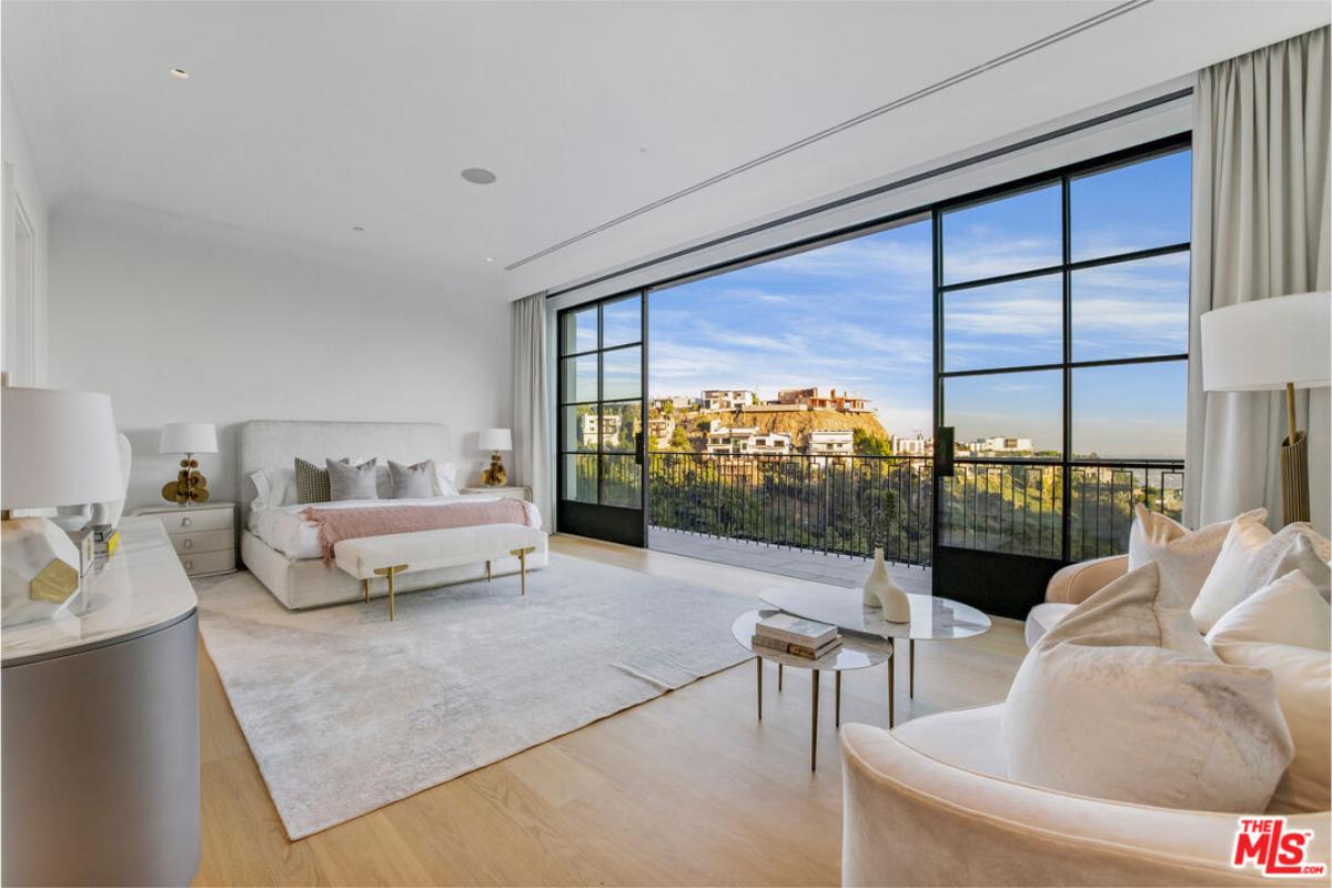 Bedroom with a large bed, sliding glass doors and a balcony.