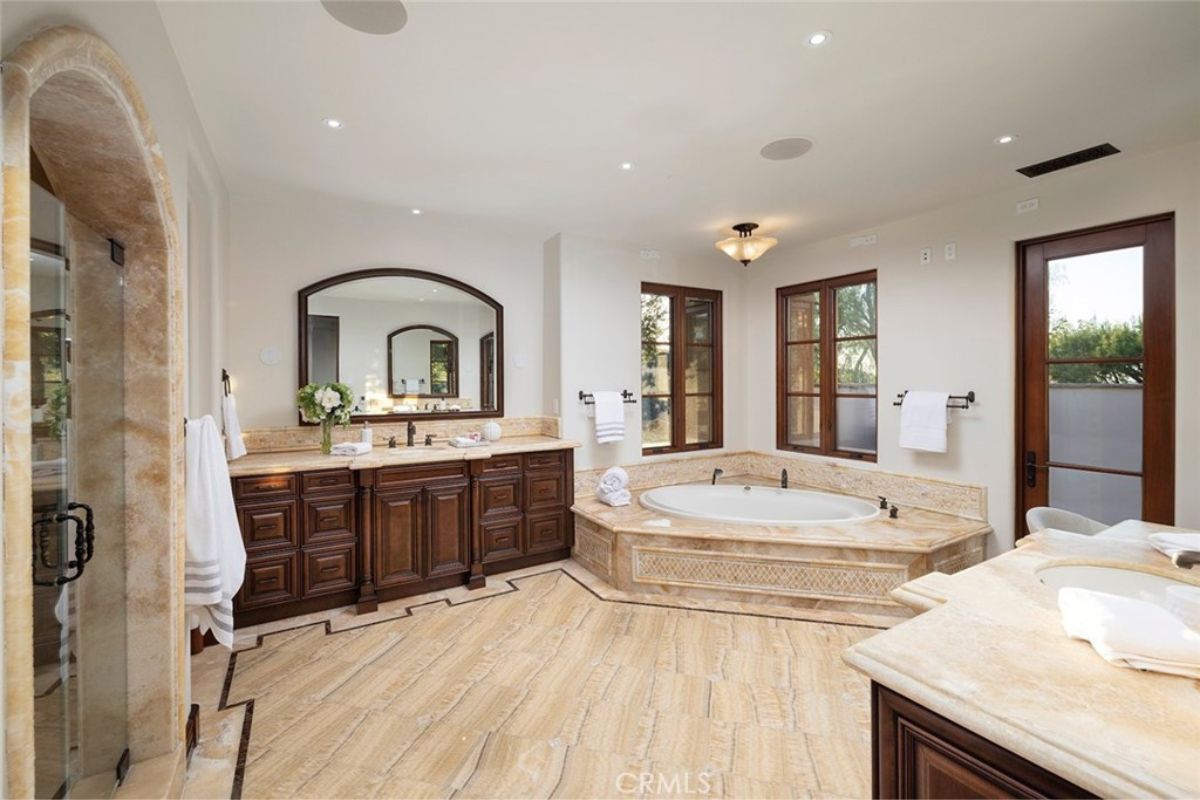 Bathroom with white ceilings and walls, a ceiling fan, bathtub, mirror, sink, and wooden cabinet.