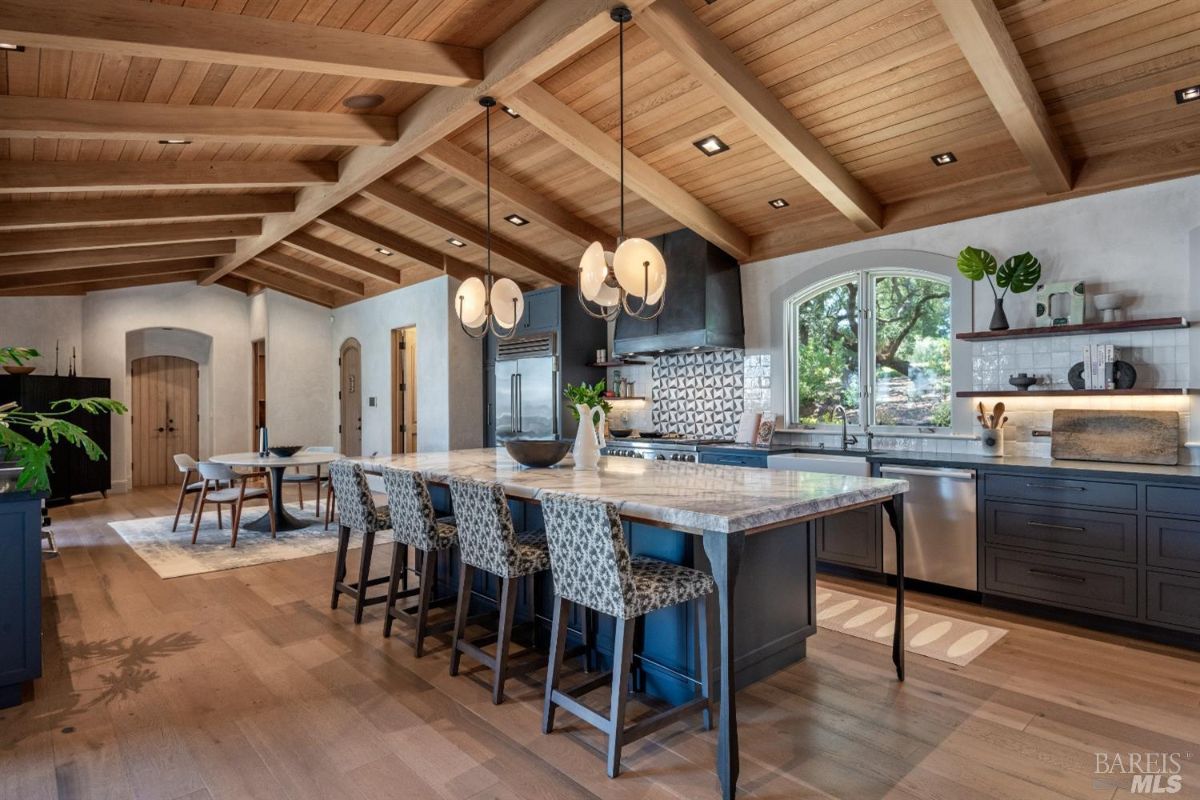 Kitchen with a large island, open beam ceiling and custom cabinets.