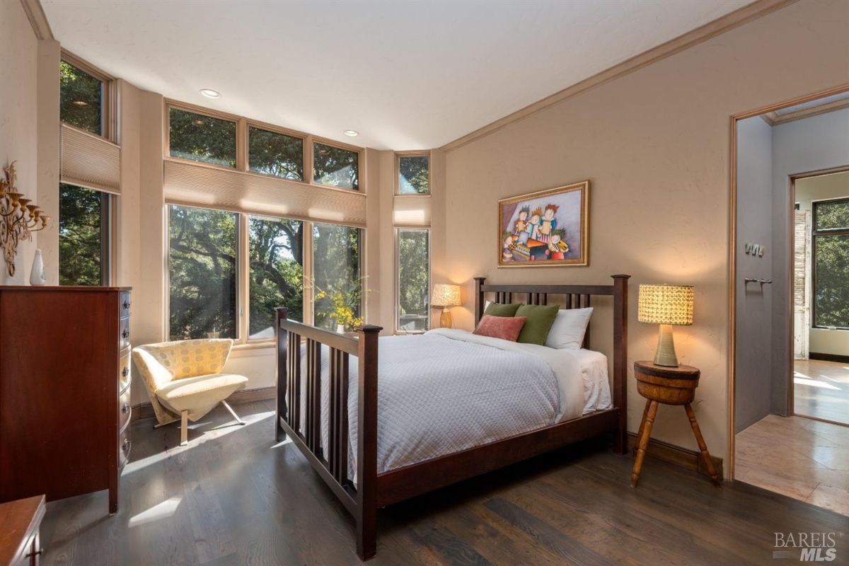 Bedroom with a large bed, wood flooring and glass windows.