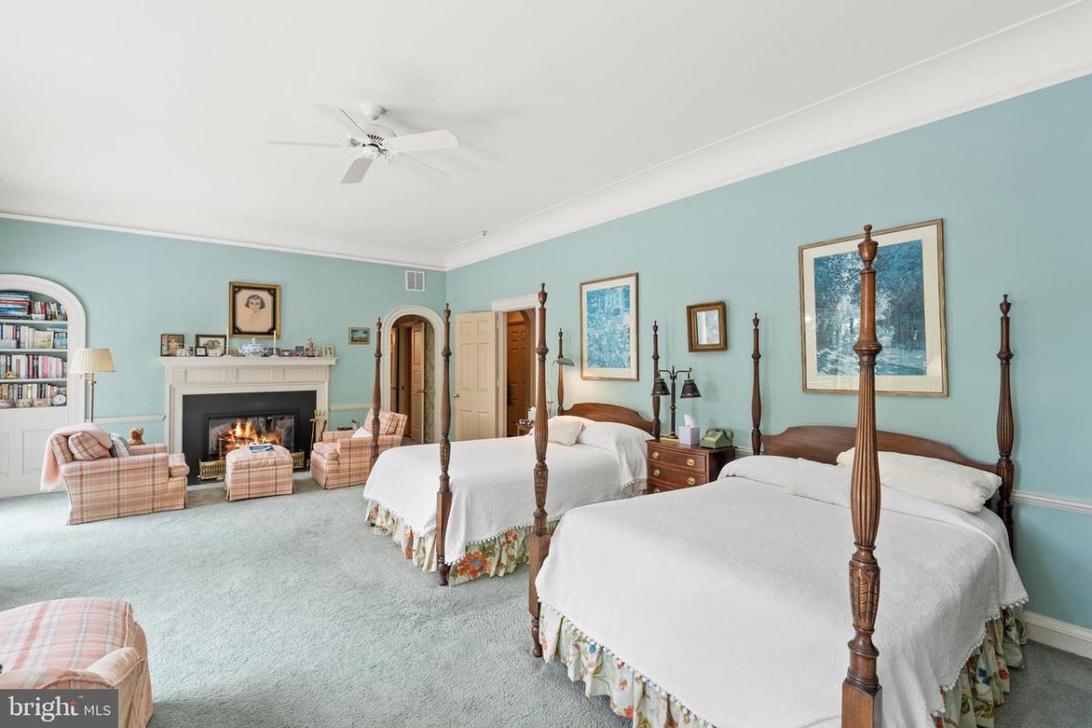 Bedroom with two beds, carpet flooring and a fireplace.