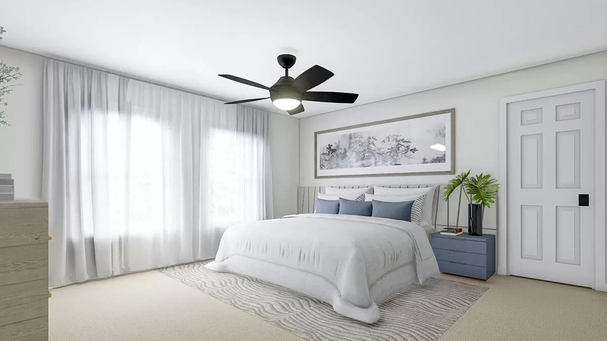 Primary bedroom with a carpeted floor and large windows dressed in sheer curtains.