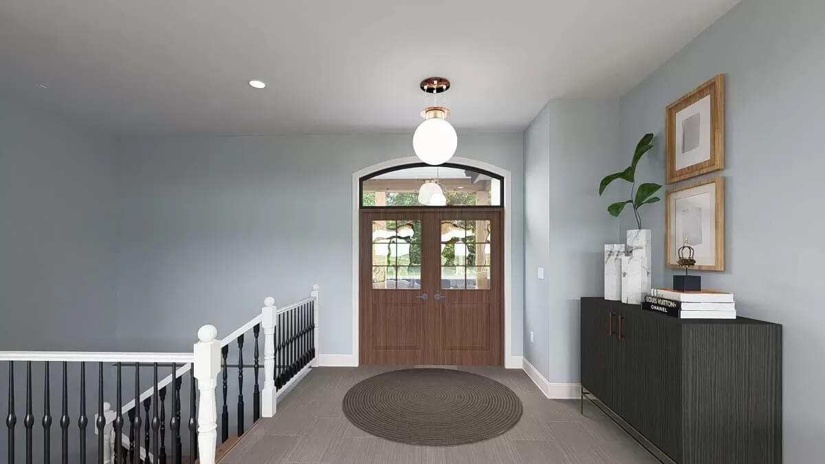 Foyer with a French front door and a black console table topped by wooden framed artworks.