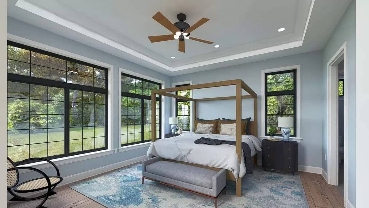 Primary bedroom with a tray ceiling and a canopy bed over the distressed area rug.