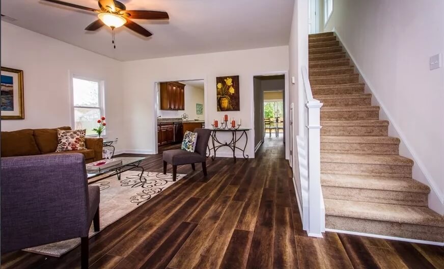 Living room with hardwood flooring and a carpeted staircase leading to the upstairs bedrooms.