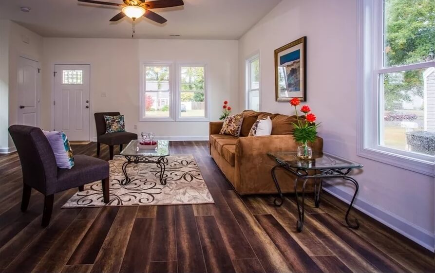 Living room with a velvet sofa, leather chairs, and a glass-top coffee table over the patterned area rug.