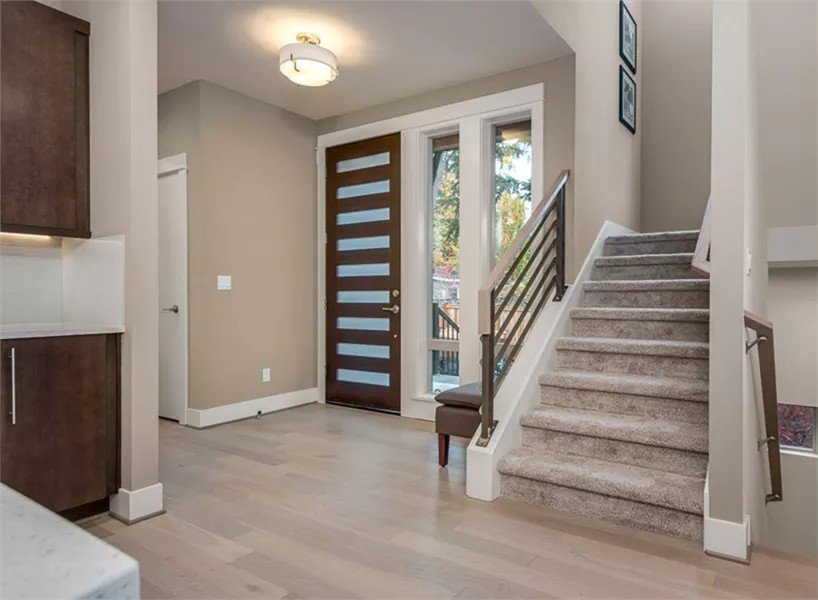 Foyer with a glazed front door and a carpeted staircase leading to the sleeping quarters.