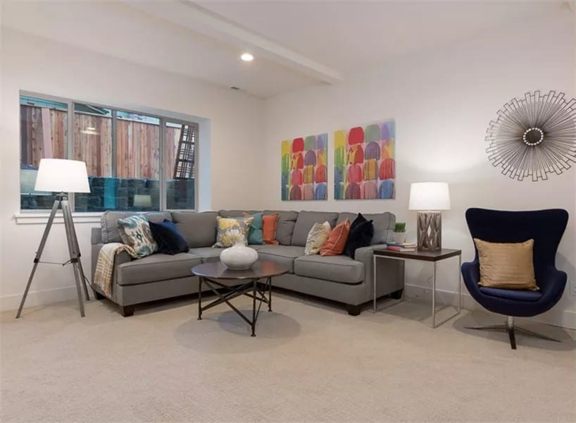 Rec room with a modern wingback chair and an L-shaped sofa paired with a round coffee table.