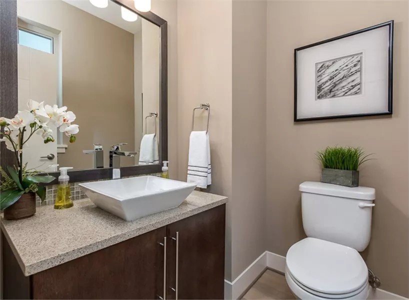 Powder room with a vessel sink vanity and a framed artwork fixed above the toilet.