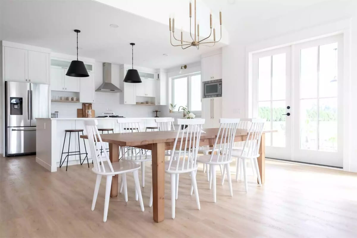 Dining area with a wooden dining table surrounded by white chairs.