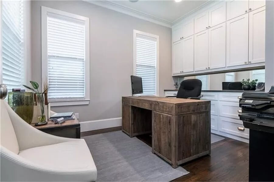 Study with white cabinets and a rustic wood desk.