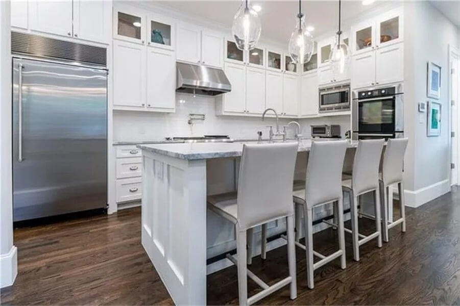 Kitchen with white cabinetry and a matching island with seating for four.