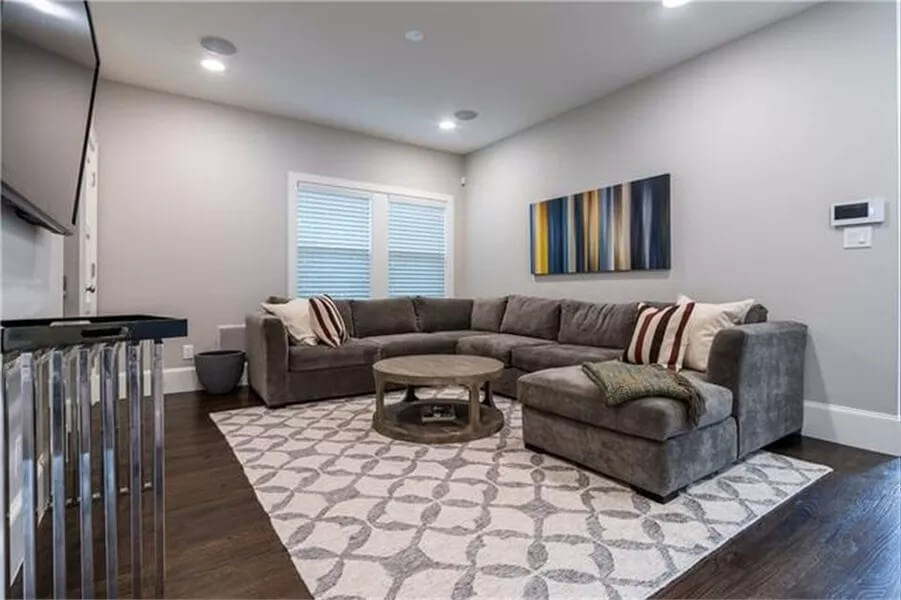 Game room with a velvet sofa and a round coffee table over the patterned area rug.