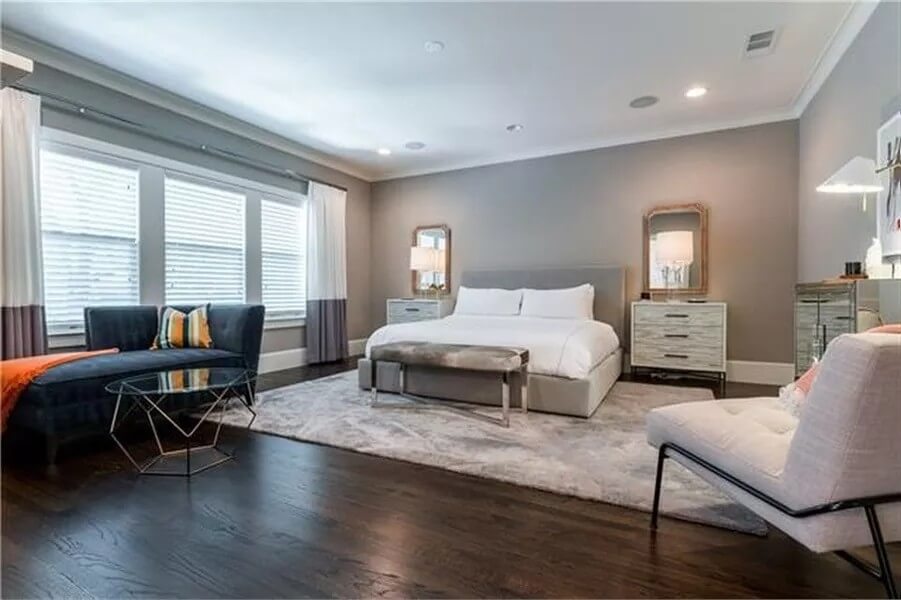 Primary bedroom with a sitting area and an upholstered bed over the velvet area rug.