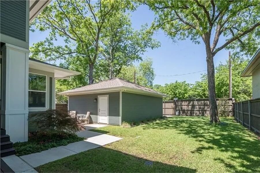 Detached garage with a white man door and a hipped roof.