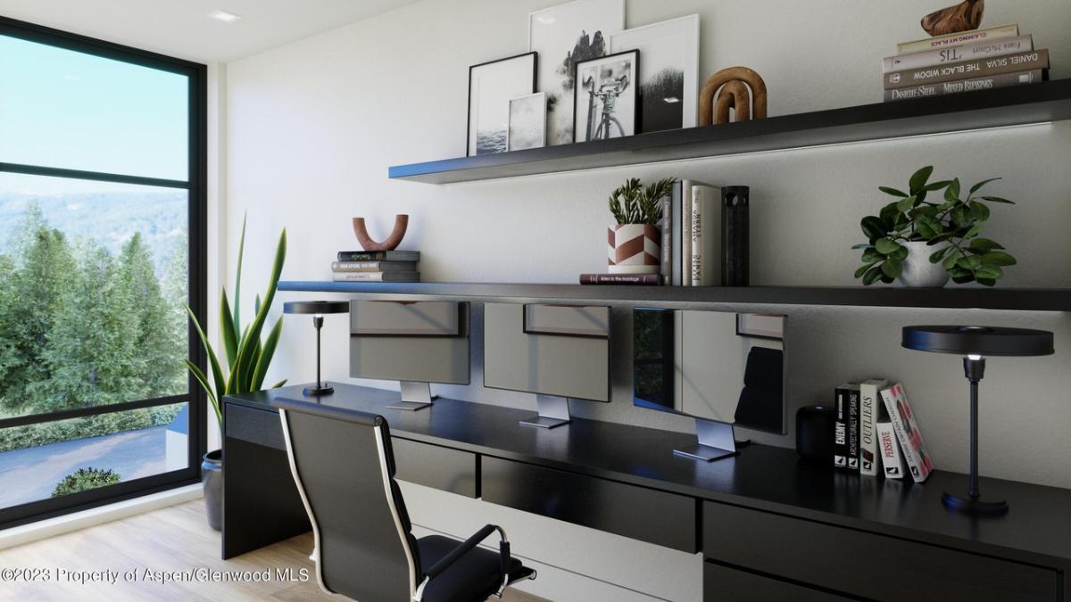 Home office with a desk, computers, chair and glass walls.