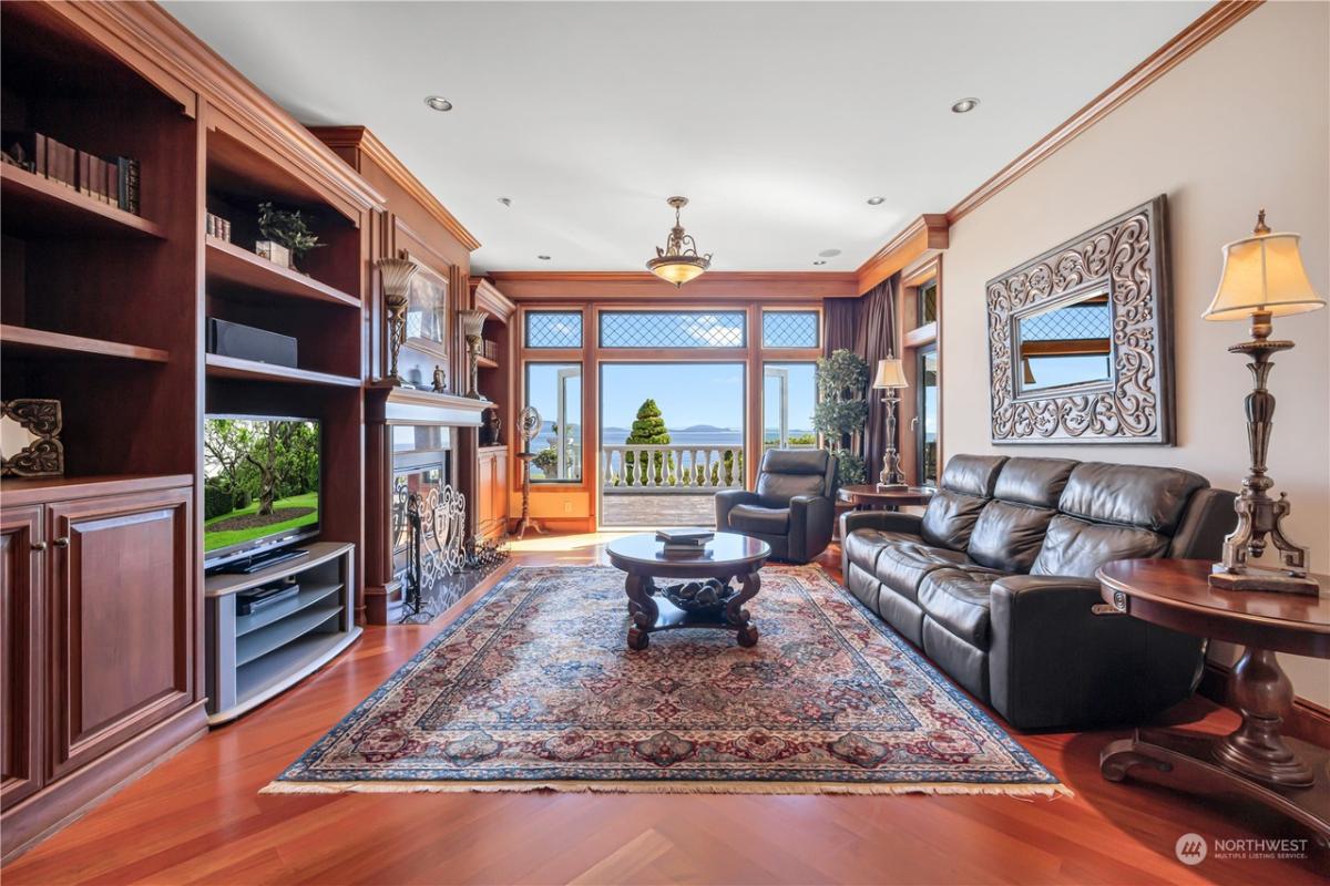 Media room with couches, TV and wood flooring.