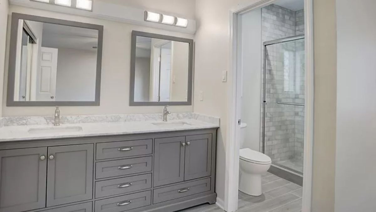 A bathroom with countertops, sinks, cabinets, mirrors, and a toilet.