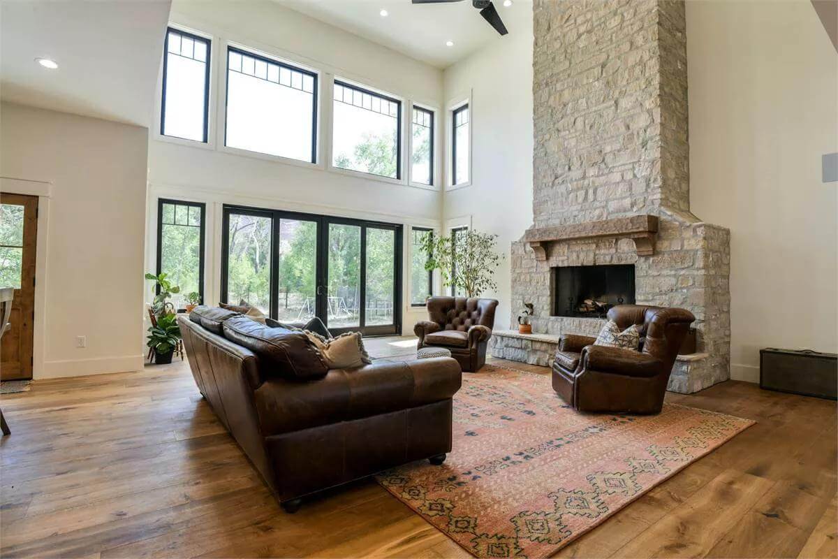 Great room with a stone fireplace and leather seats over the area rug.