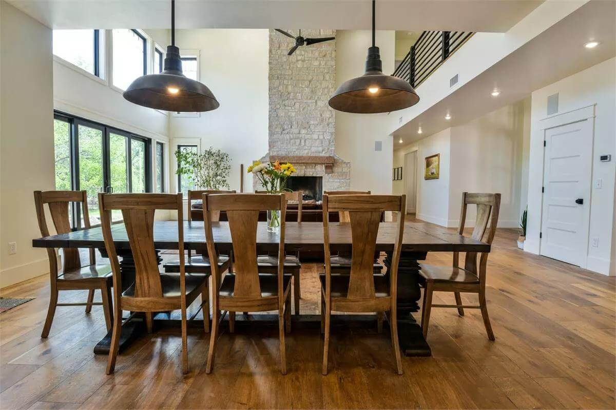 Dining room with high back chairs and a dark wood table illuminated by oversized dome pendants.