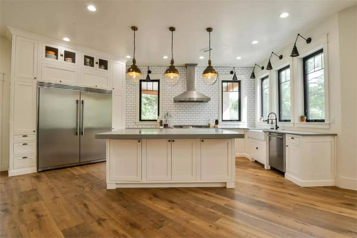 Kitchen with white cabinets and a matching island topped with glass-globe pendants.