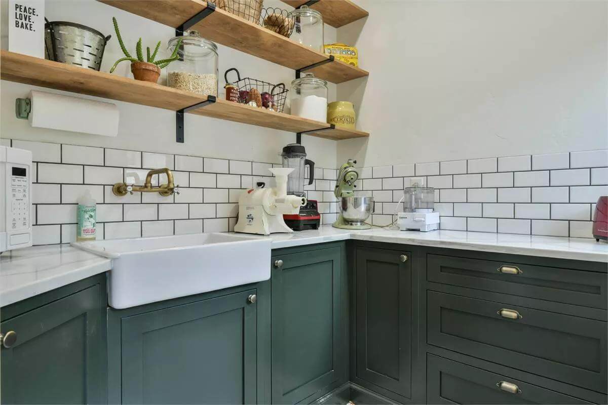 Kitchen pantry with gray cabinets, floating shelves, and a farmhouse sink.