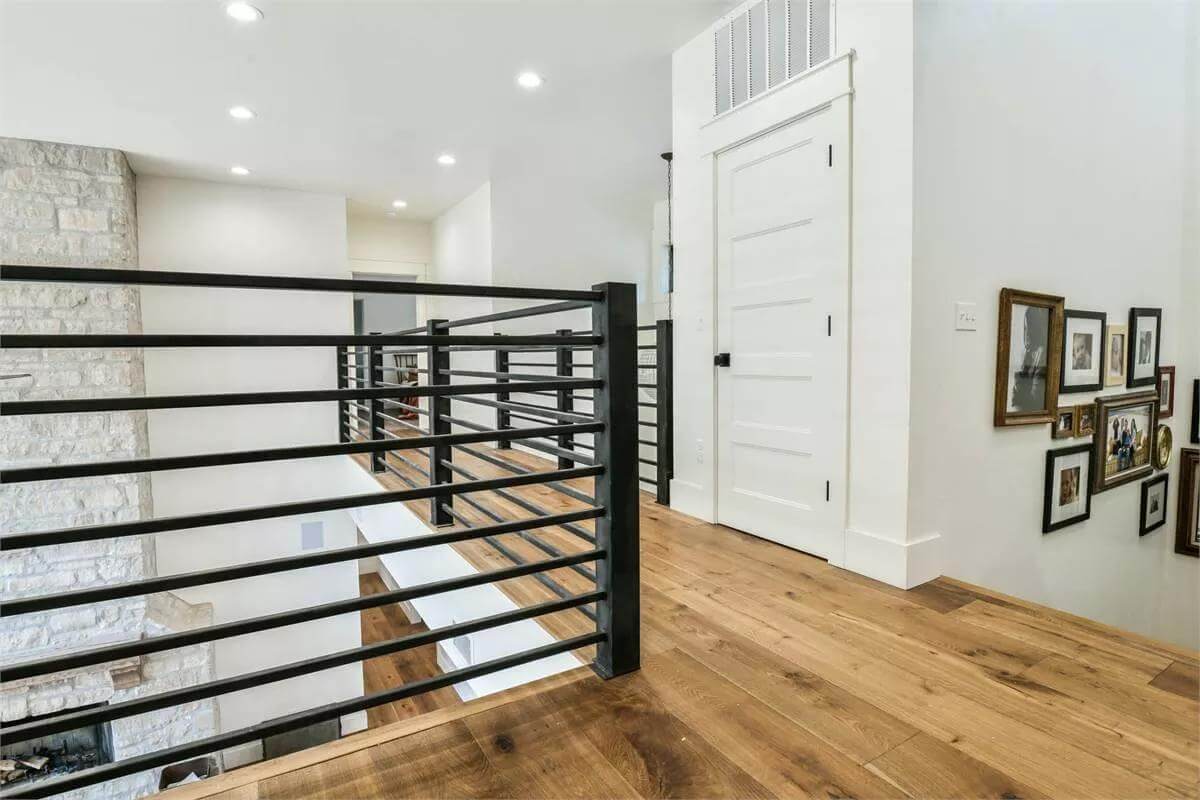 Upstairs hall with wrought iron railings and a hardwood floor.