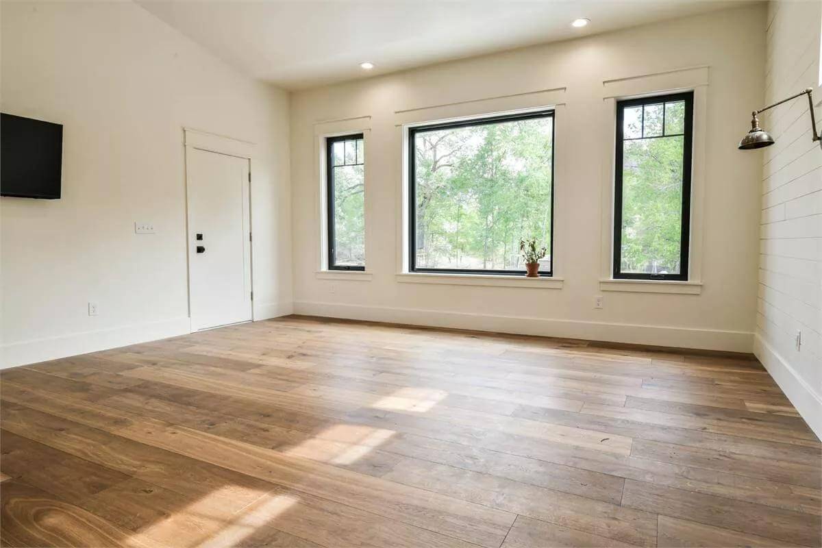 Primary bedroom with a hardwood floor and black-framed windows.