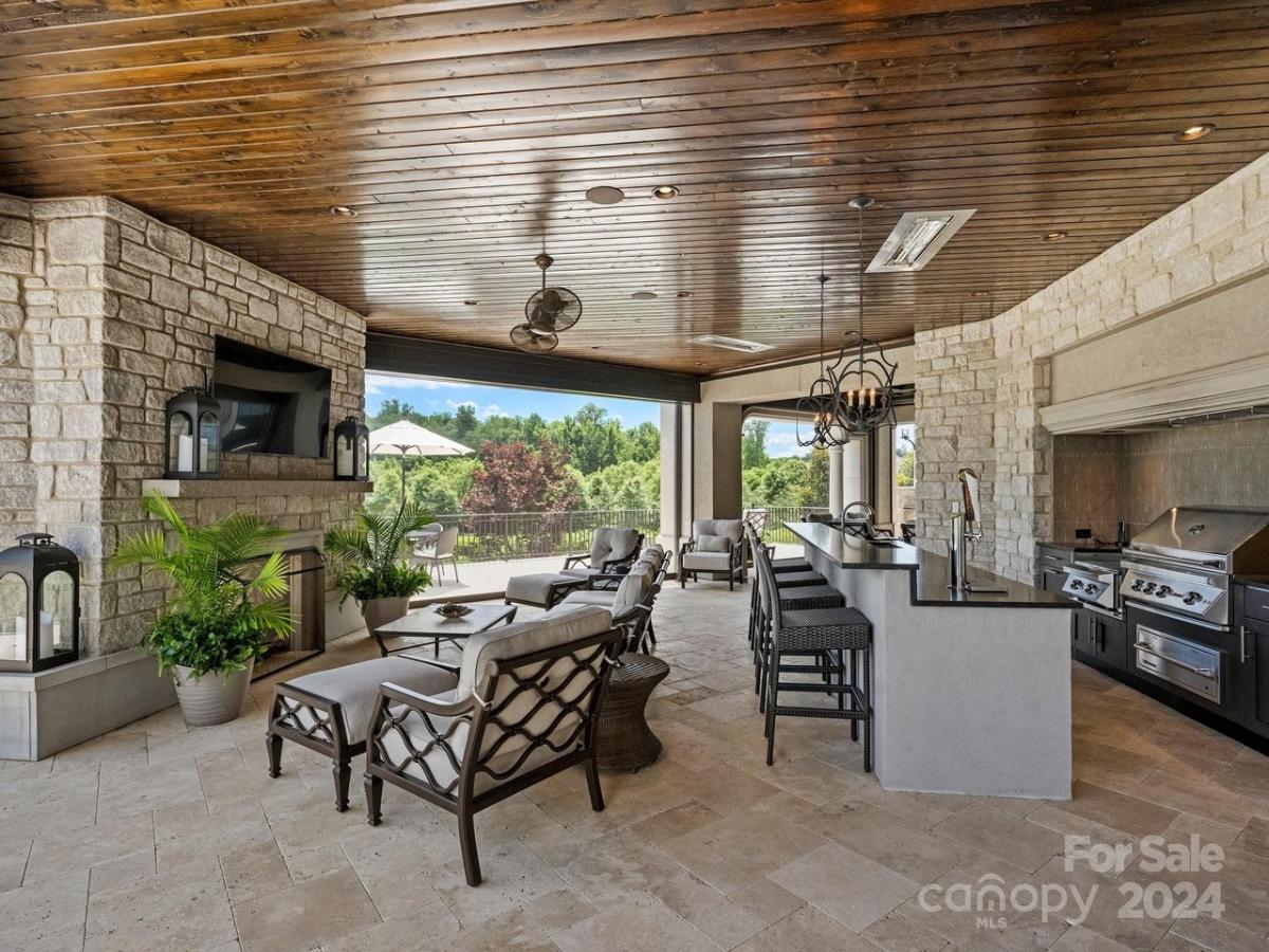 Covered patio with tables, chairs and a grill area.