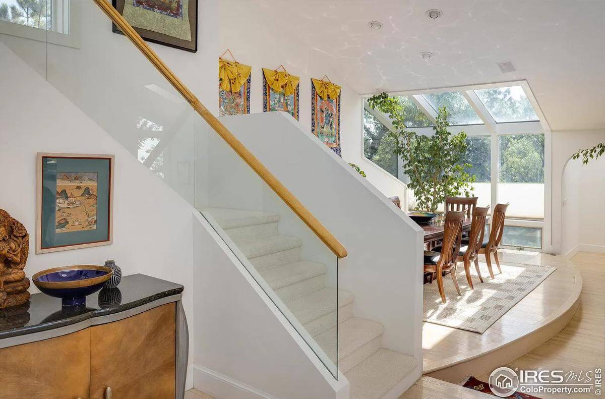 Foyer with a wooden console table and a carpeted staircase with glass railings.