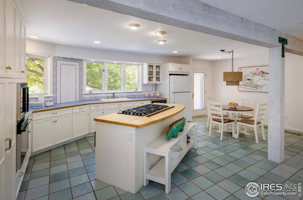 Kitchen and breakfast nook with white cabinets, a cooktop island, and around dining set.