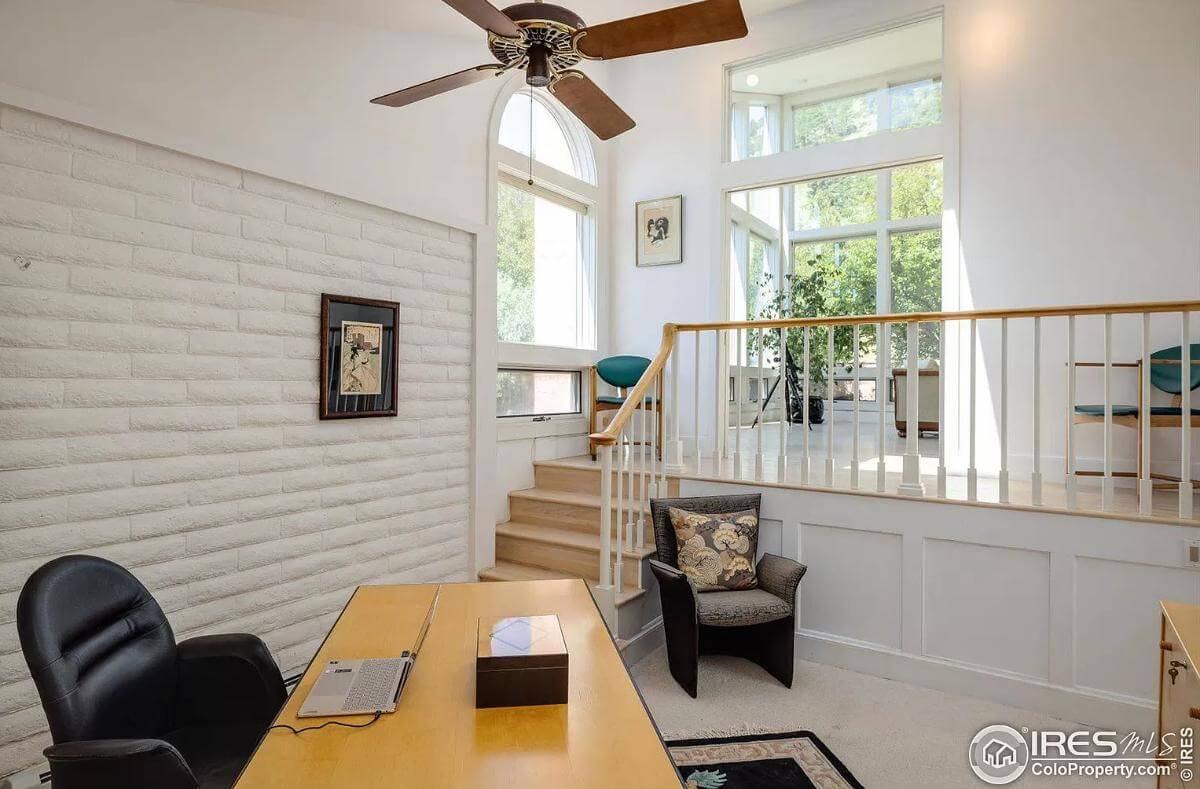 Office with a wooden desk and black chairs over the carpeted floor.