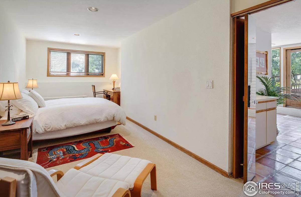 Bedroom with a platform bed, a wooden desk, and a lounge chair over the carpeted floor.