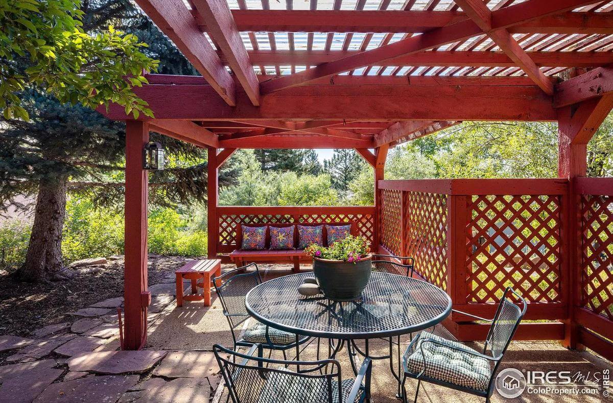 Pergola porch with wooden benches and an iron dining set.