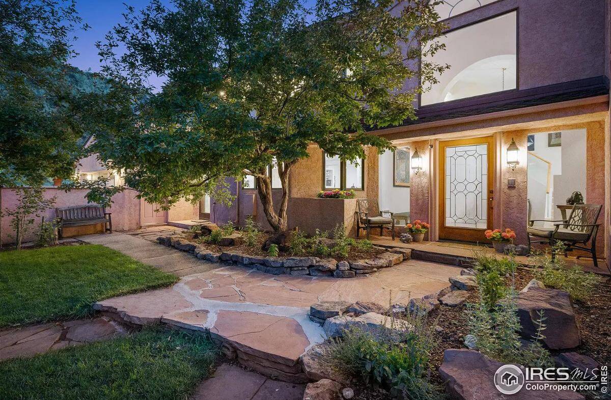 Front porch with a glazed front door and cushioned chairs.