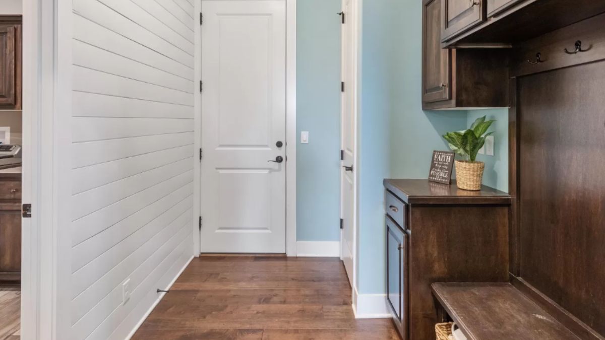 A mudroom with wooden floor, cabinets, and a bench.