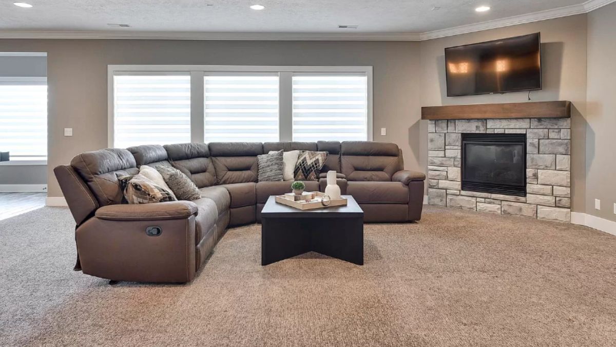 A family room with windows, TV, fireplace, couch, and a center table