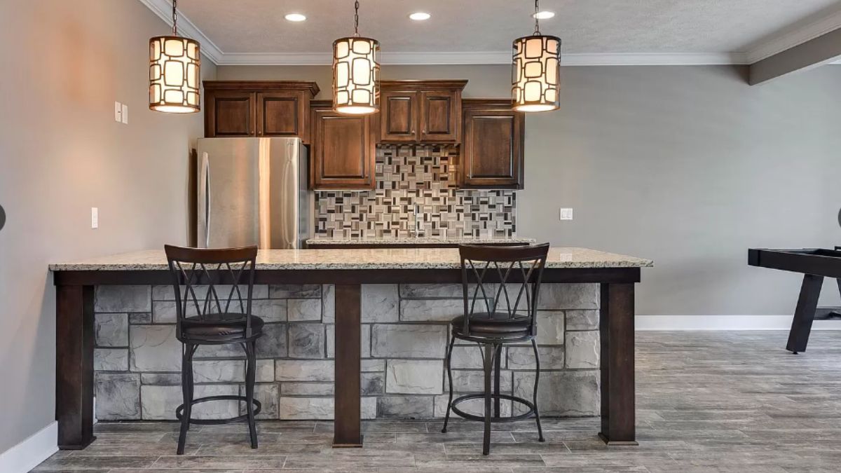 A bar with countertop, cabinets, and stools.